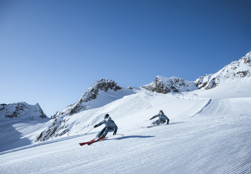 Skifahrerin und Skifahrer im Frühling auf Piste am Stubaier Gletscher